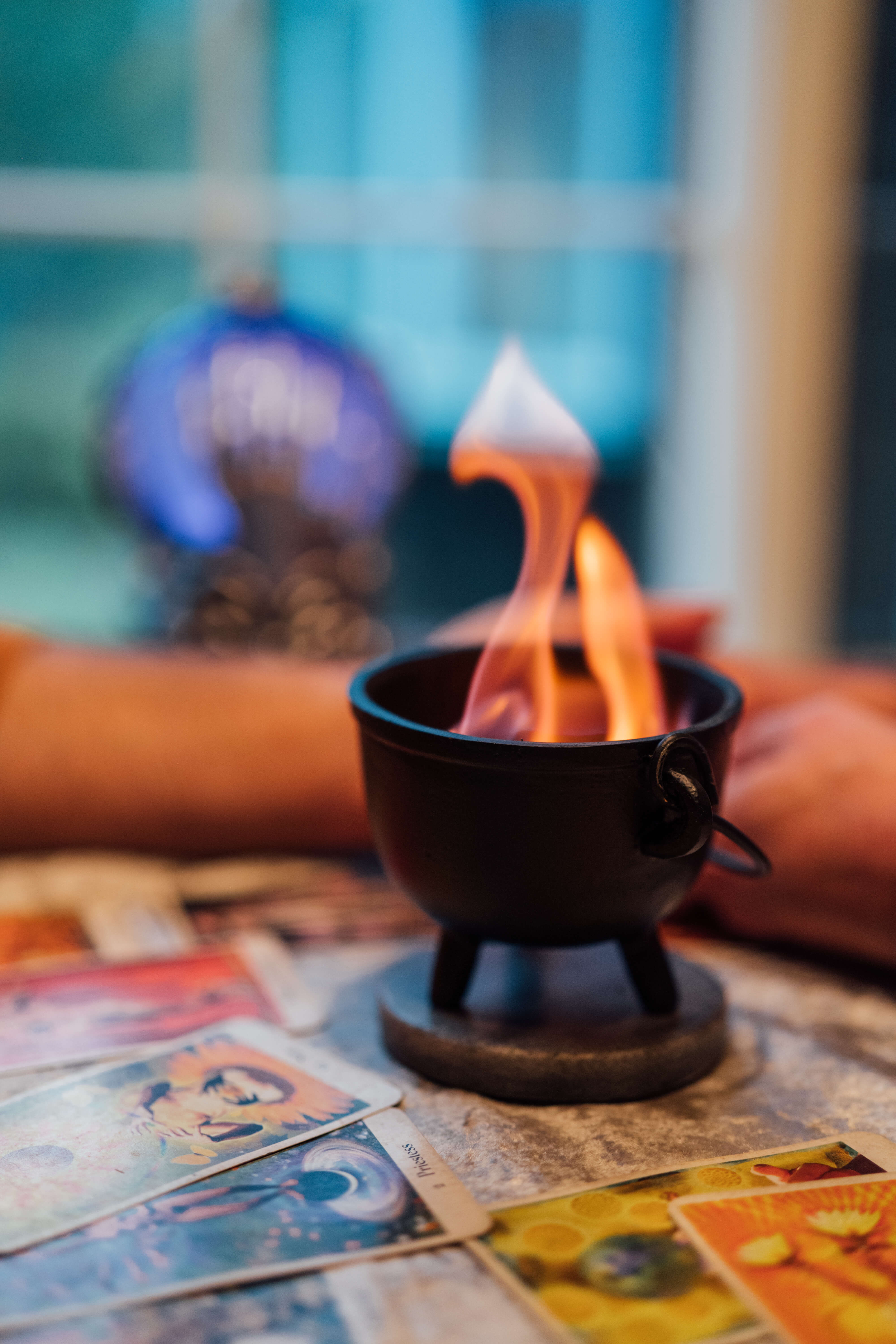Small cauldron with candle flame on tarot spread